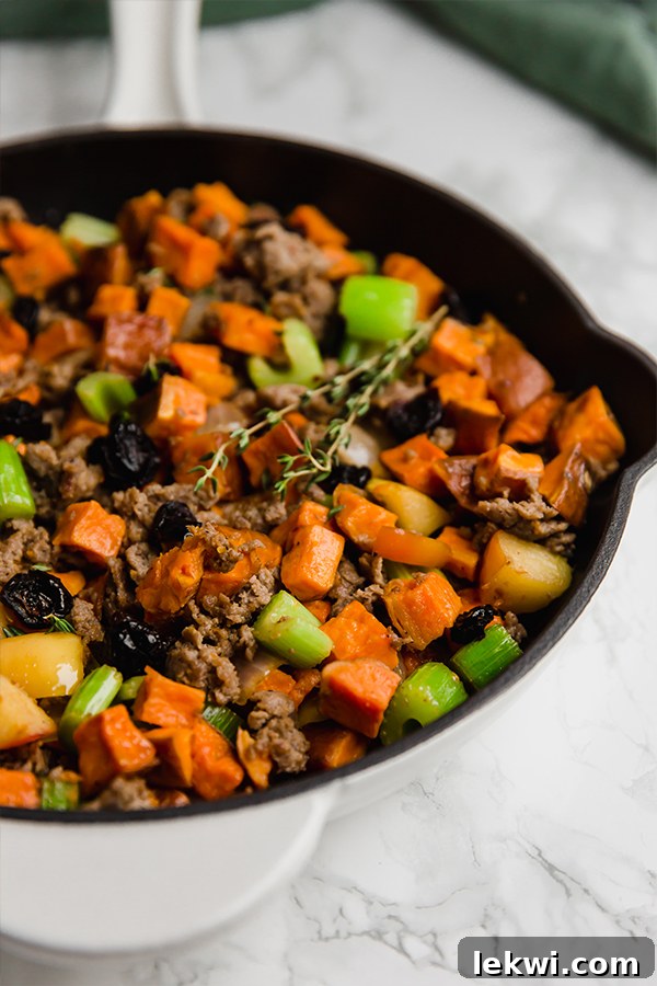 A baking dish filled with savory sweet potato sausage stuffing, freshly cooked and ready to serve.