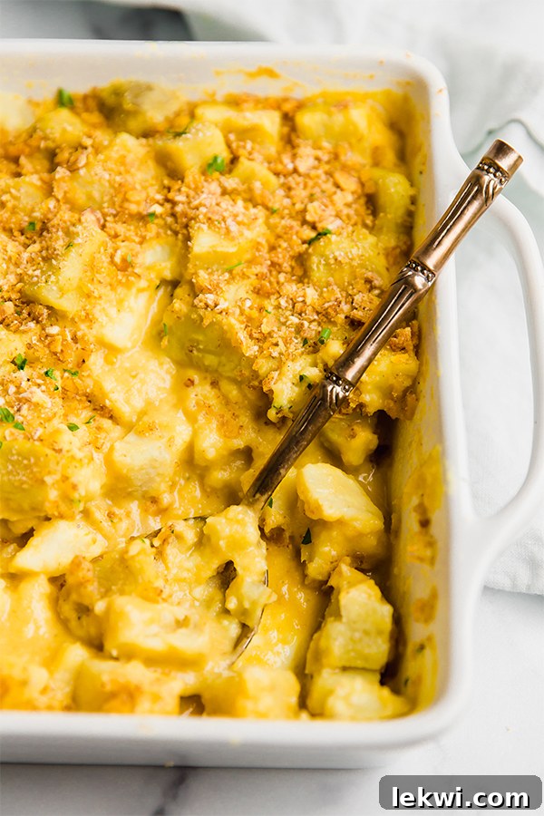 A pristine white baking dish generously filled with a golden, creamy 'cheesy' sweet potato casserole.