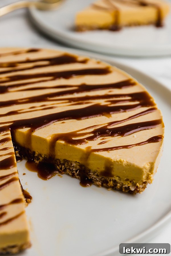 A beautiful pumpkin cheesecake sitting on a white plate, with one perfect slice carefully cut out.