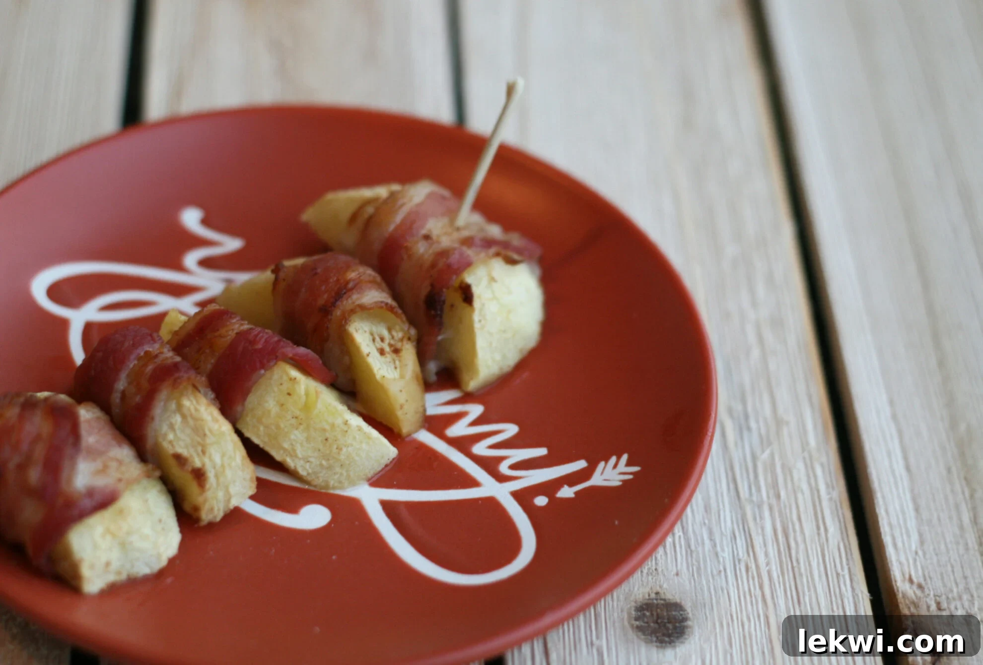 Close-up shot of golden-brown Pumpkin Spice Bacon Wrapped Apples, artfully presented on a light-colored platter.