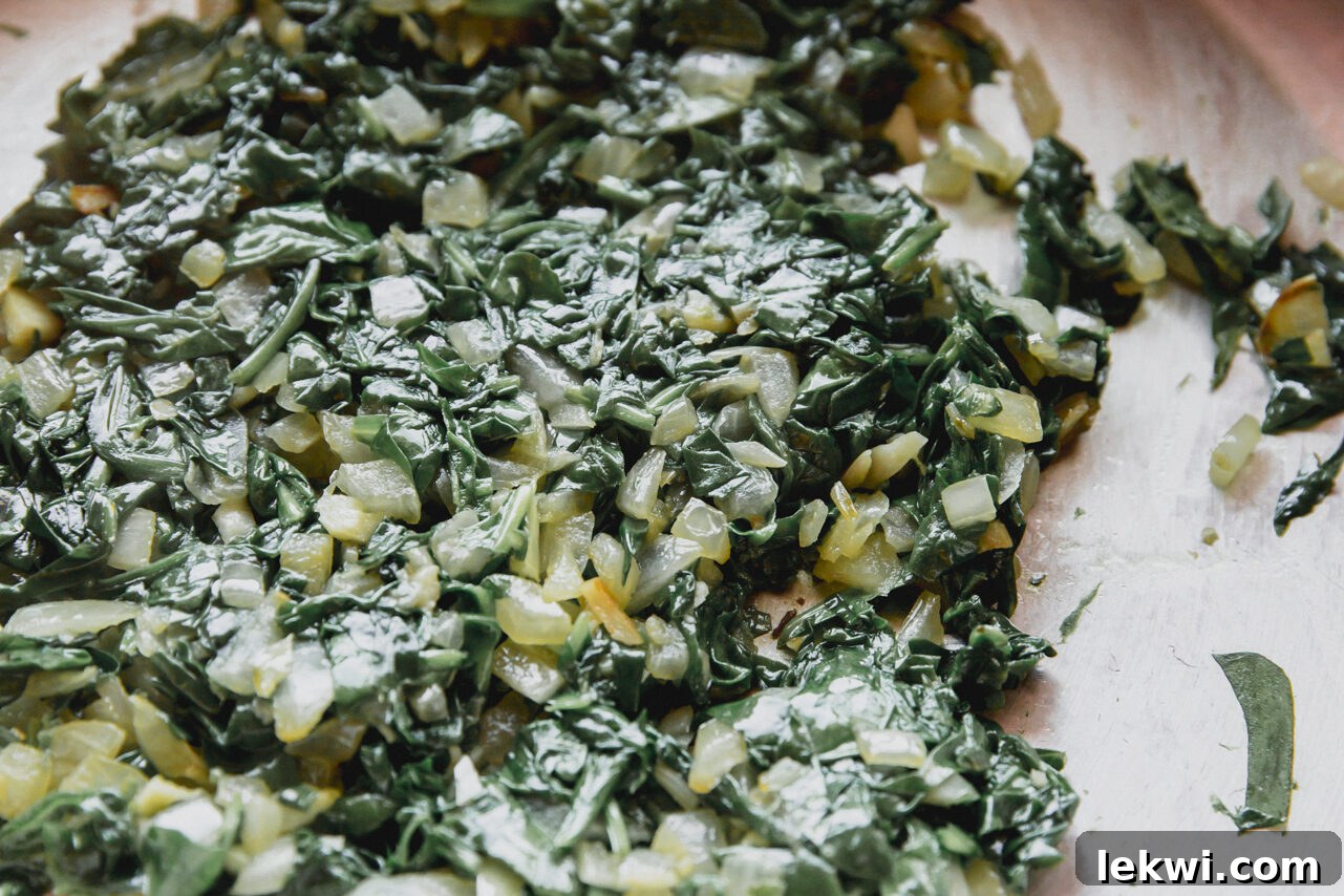 Spinach, onion, and garlic sautéing in a pan, filling the kitchen with fragrant aromas.