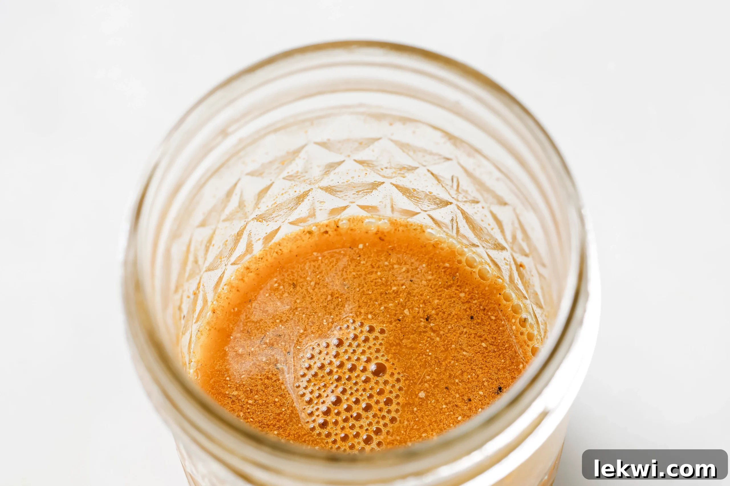 A glass jar filled with ingredients for an apple cider vinegar shot being mixed, demonstrating the first step.