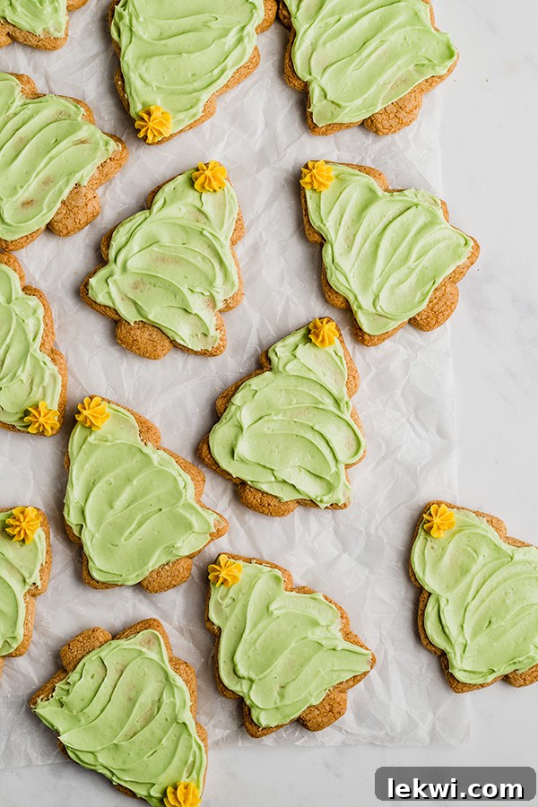 Many sugar cookies shaped like a Christmas tree with green icing and a yellow icing star on top.