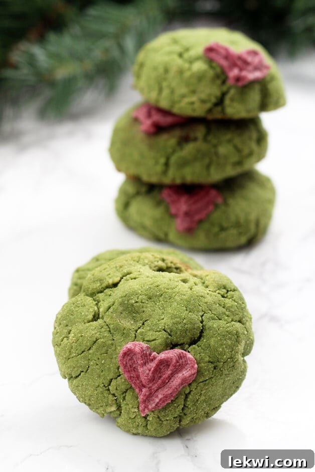 A grinch cookie in front of a stack of grinch cookies positioned behind it.