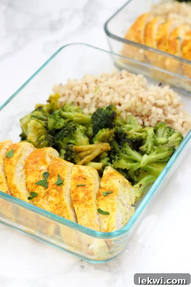 A meticulously arranged glass meal prep container showcasing golden turmeric chicken, vibrant green broccoli, and fluffy white rice.