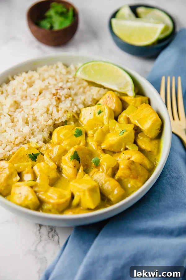 A white bowl filled with cauliflower rice and turmeric chicken curry.