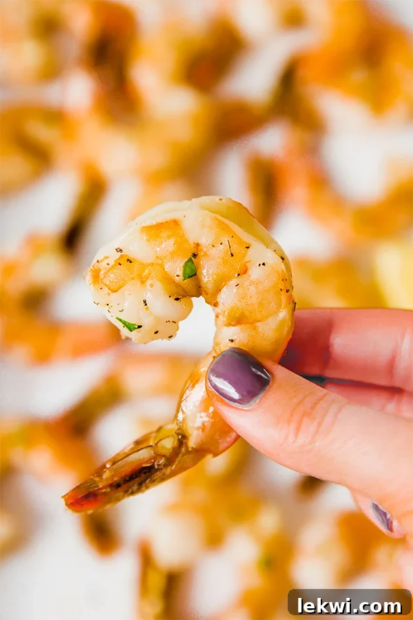 A hadn holding a baked shrimp with its tail on.