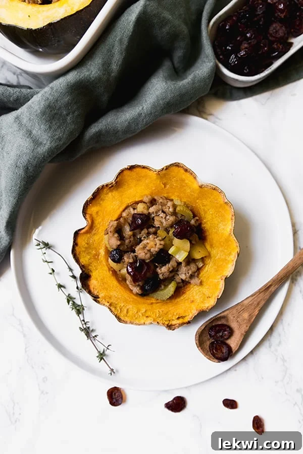 A plate with a stuffed acorn squash and a wooden spoon next to it.