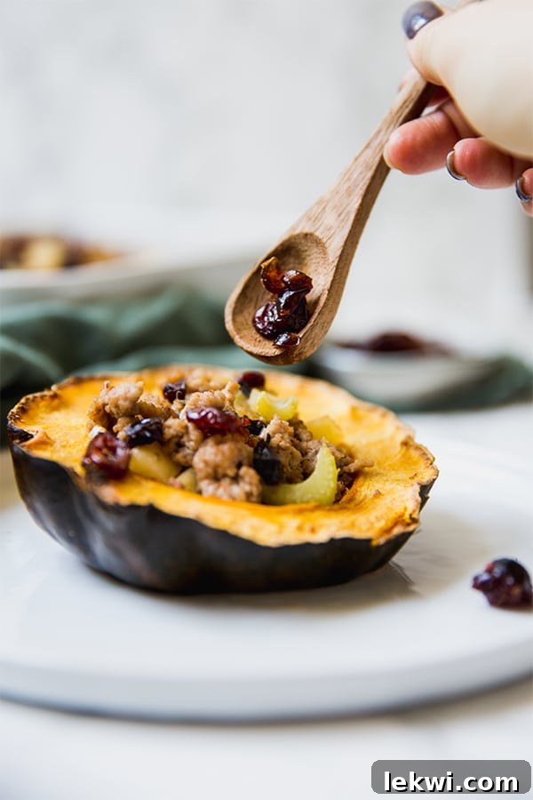 A wooden spoon putting some stuffing into an acorn squash.