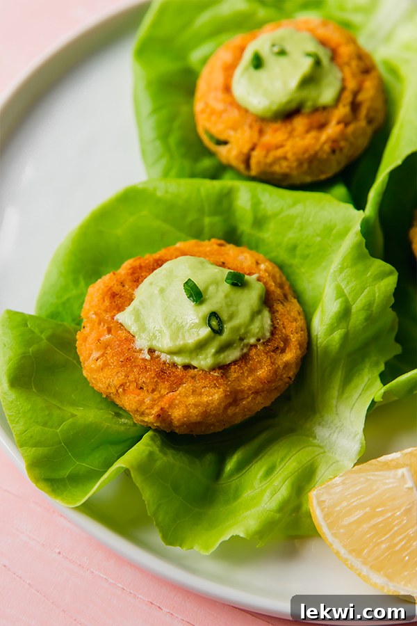 Sweet Potato Crab Cakes, perfectly golden brown and served on a bed of fresh greens with a lemon wedge.