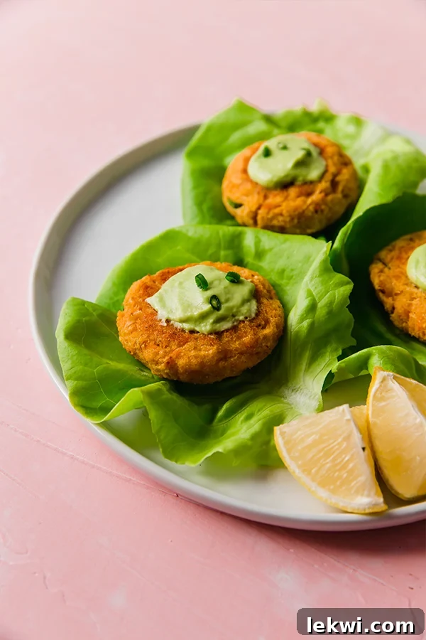 Sweet potato crab cakes on pieces of lettuce on a plate with wedges of lemon next to it, ready to be served.