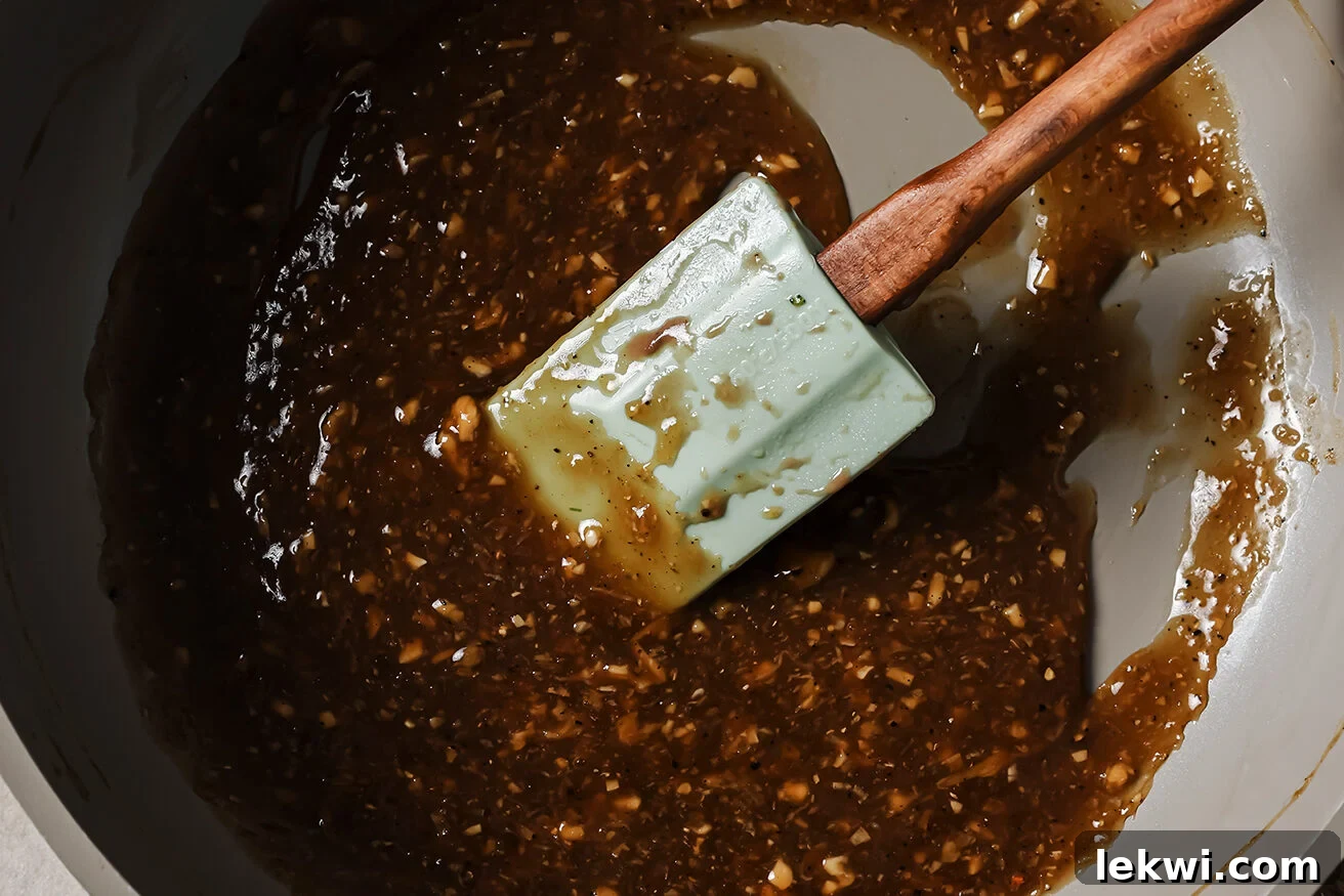 Savory sauce simmering in a pan, stirred with a wooden spoon.