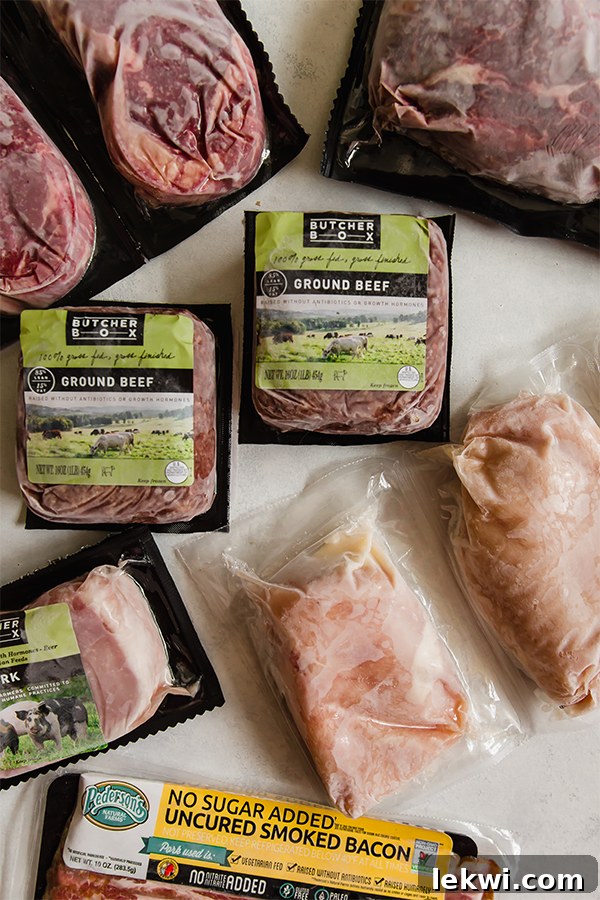 Assorted high-quality meats from ButcherBox, including steaks and ground beef, carefully frozen on a kitchen counter, ready for meal preparation.