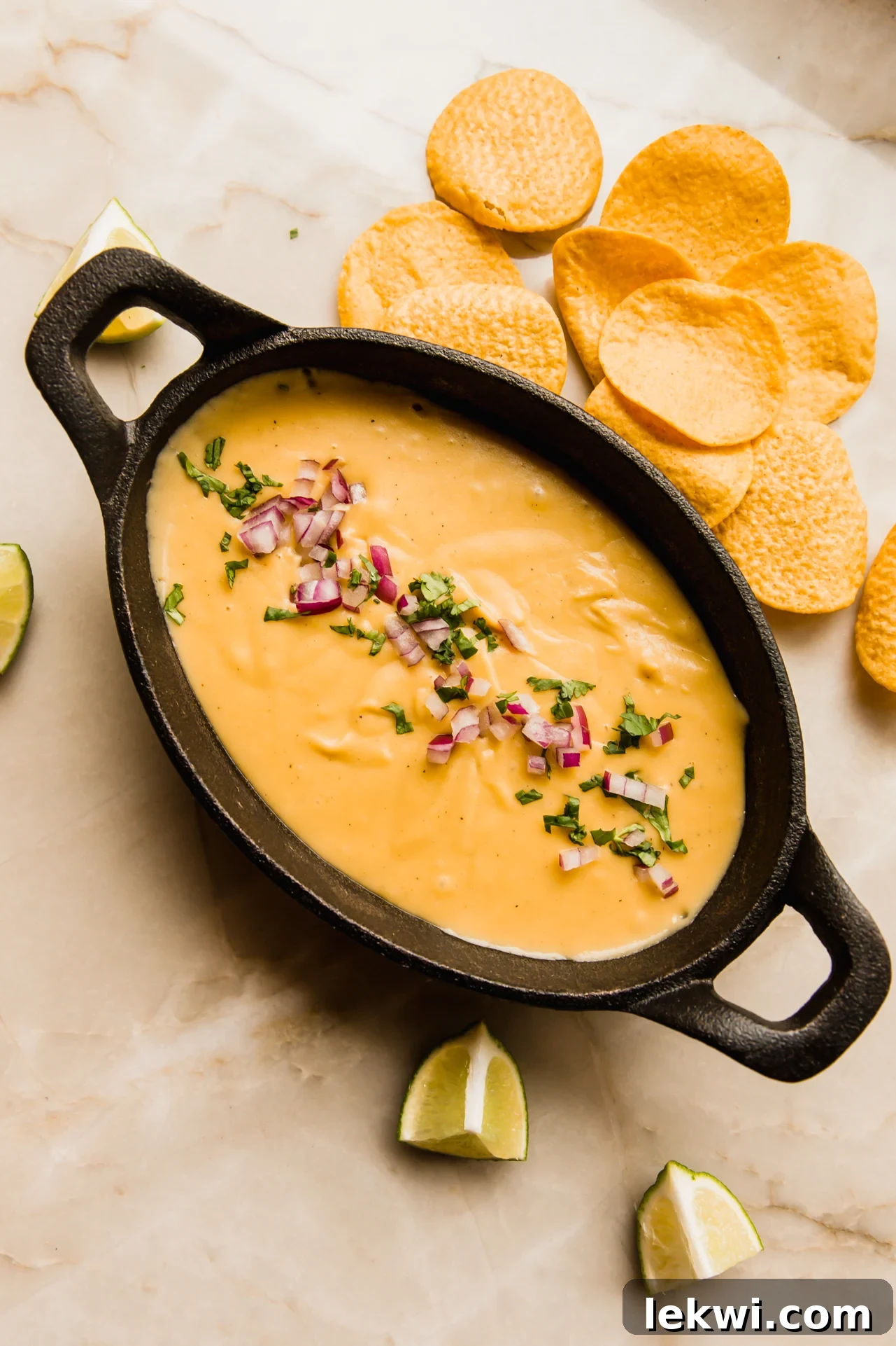 Vegan queso in a serving dish, garnished with fresh red onion and cilantro.