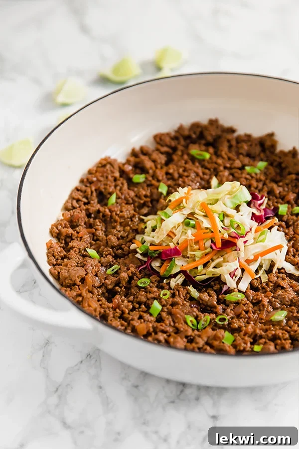 A white skillet filled with asian sloppy joes and topped with coleslaw mix.