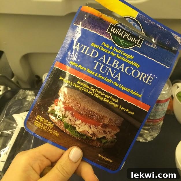 A prepared meal in a container with roasted vegetables, tuna, and avocado.