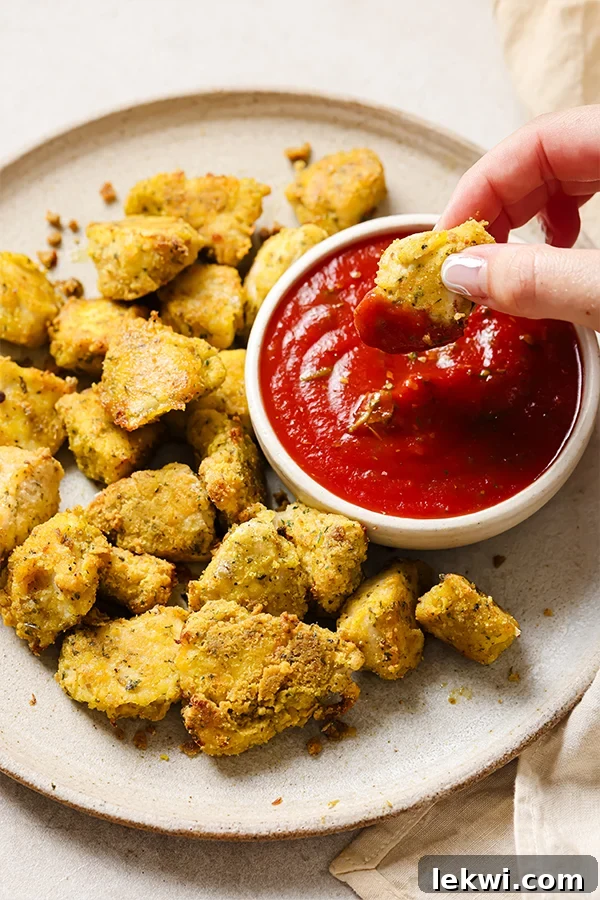 Plate of crispy Italian chicken nuggets with dip, garnished with fresh parsley.