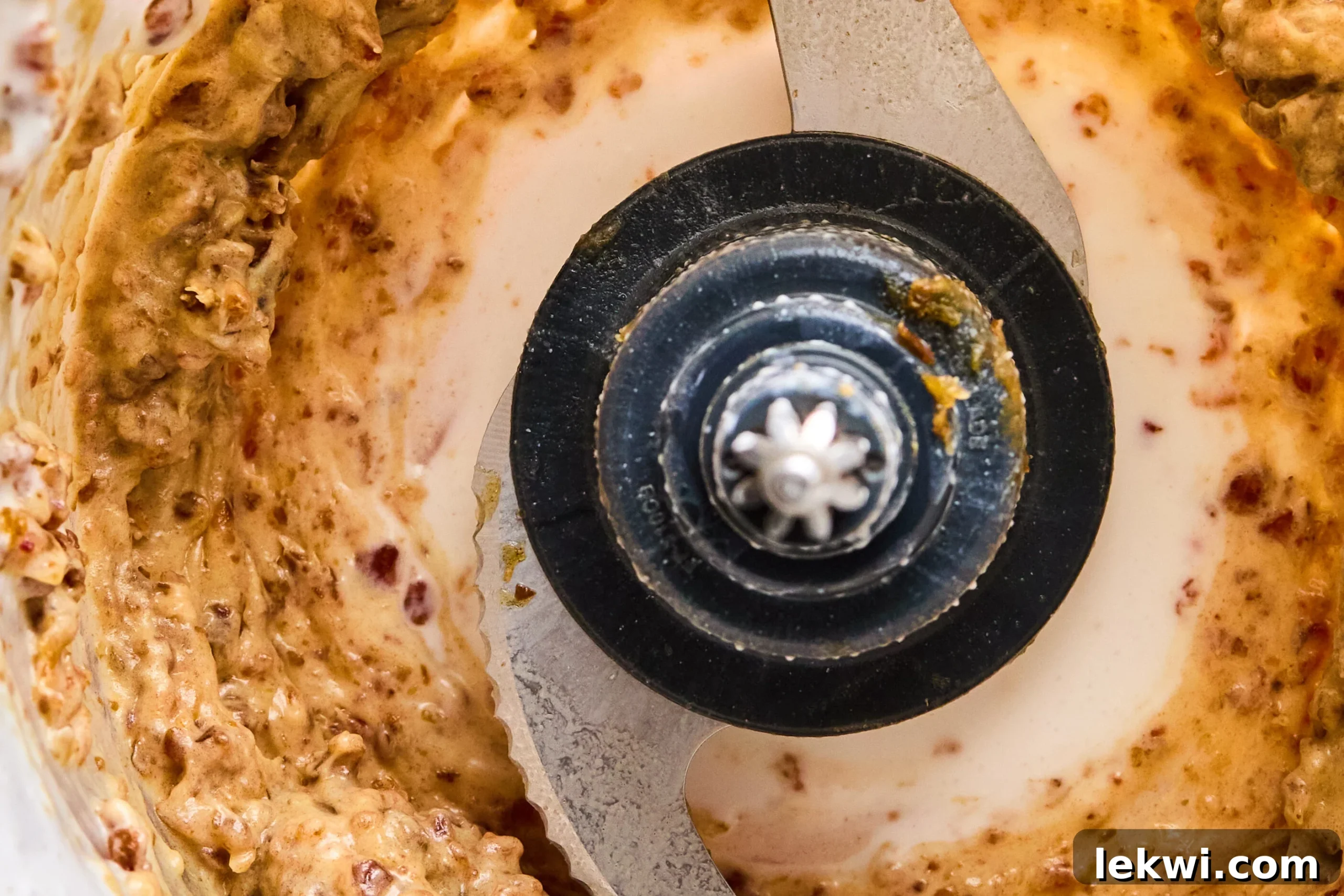 A food processor bowl containing a thick, creamy paste formed from blended dates and coconut milk, representing the rich caramel topping.