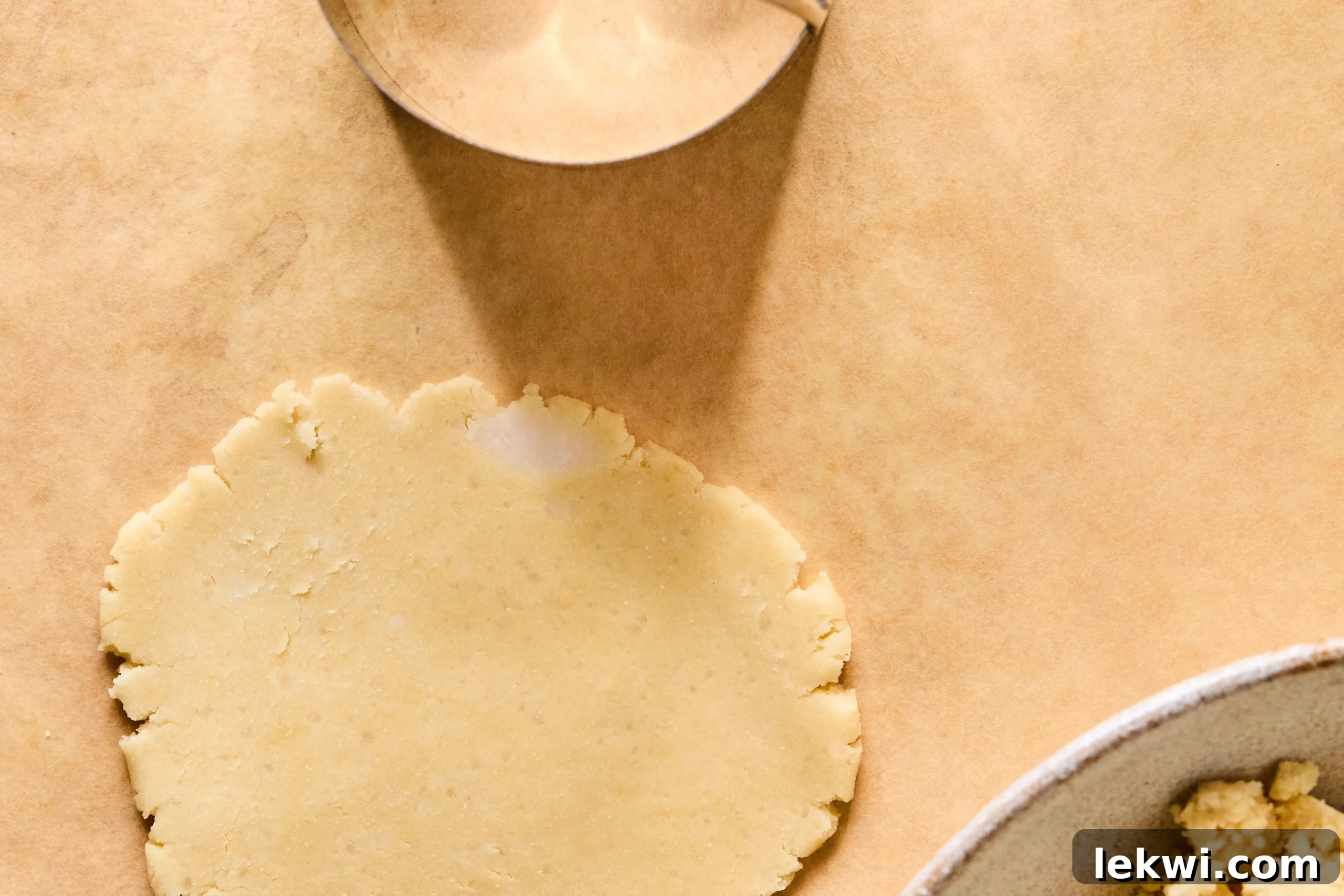 Cookie dough gently flattened on a sheet of parchment paper, ready to be cut into perfect Samoa cookie shapes.