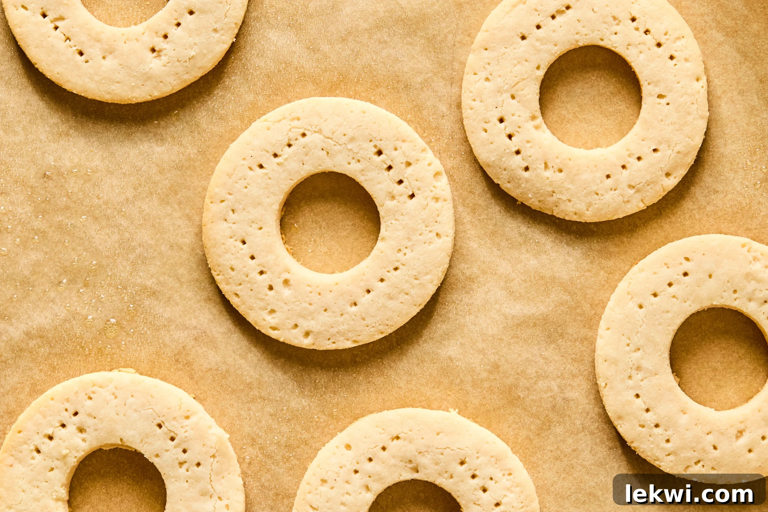 Golden-brown, perfectly baked cookie dough circles resting on parchment paper after being removed from the oven and cooling.