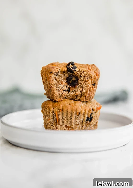 Two perfectly baked carrot cake muffins, golden brown and inviting, displayed against a soft, light background.