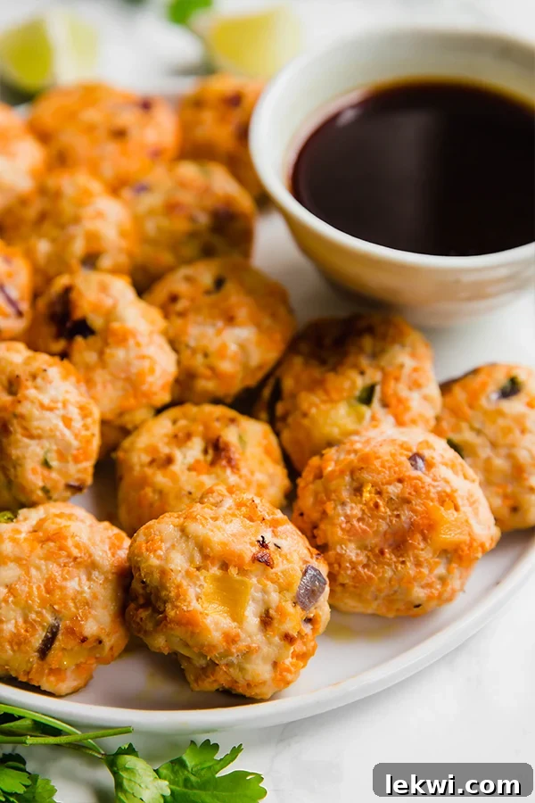 A white plate with pineapple chicken poppers with dipping sauce next to it.