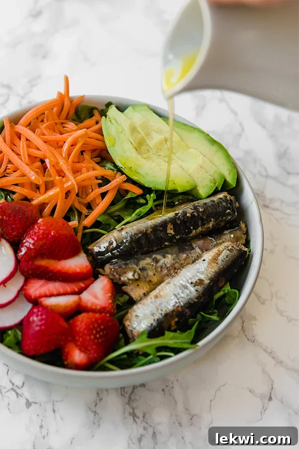 A vibrant sardine salad with fresh greens, vegetables, and fruit.