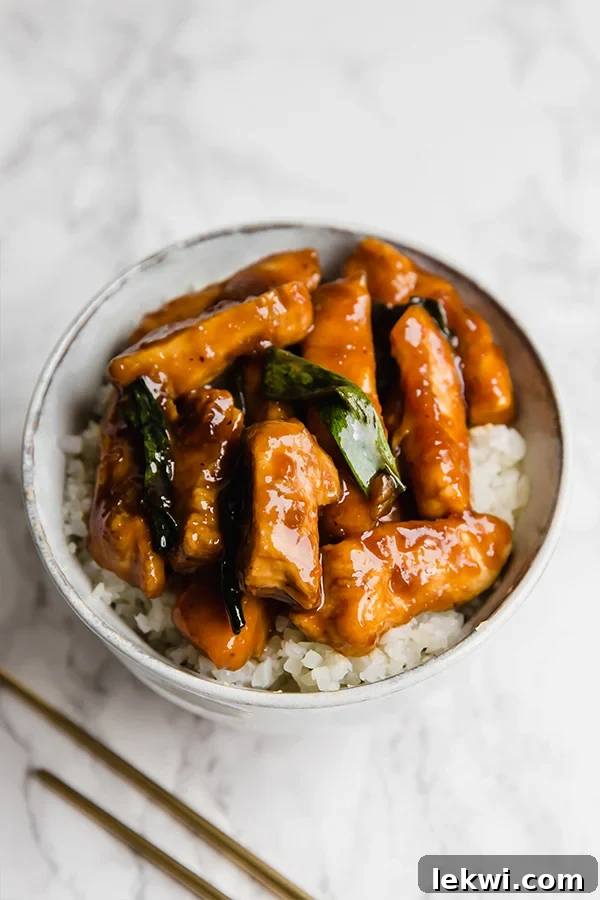 A white bowl filled with cauliflower rice topped with Mongolian chicken.