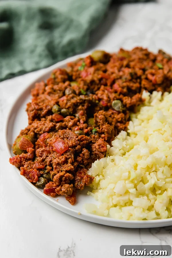 A white plate with picadillo and cauliflower rice on it.