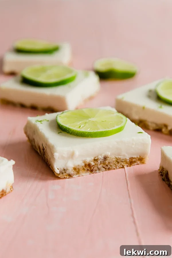 Delicious Paleo Key Lime Pie Bars on a serving platter, topped with fresh lime slices and zest, ready to be enjoyed.
