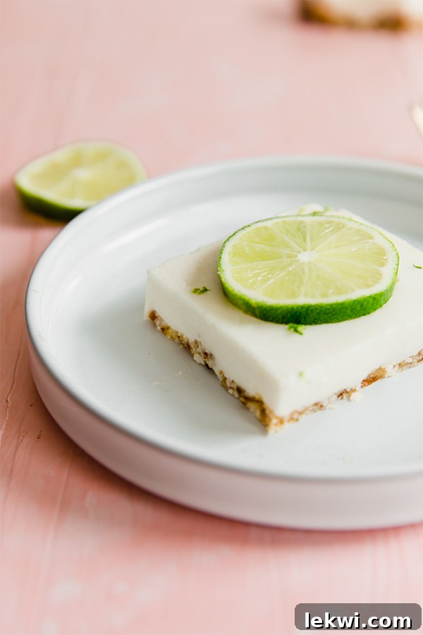 Close-up of paleo key lime pie bars, showing their vibrant green filling and a dusting of fresh lime zest, inviting a refreshing bite.