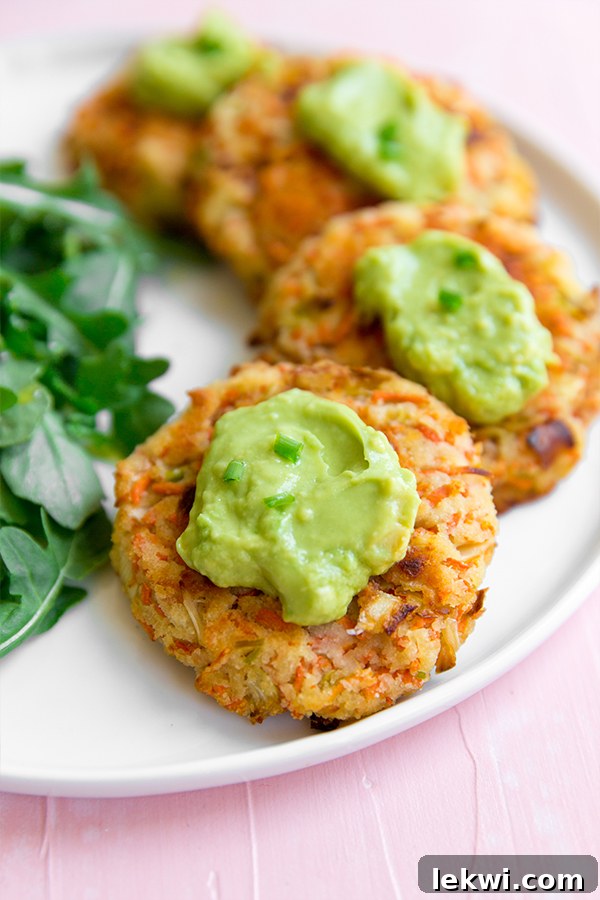 Crispy carrot bacon breakfast fritters arranged on a plate with a side of dipping sauce.