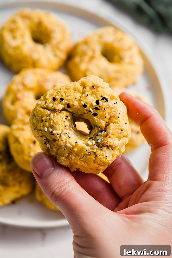 A hand holding a perfectly golden cauliflower everything bagel bite, showcasing its textured surface.