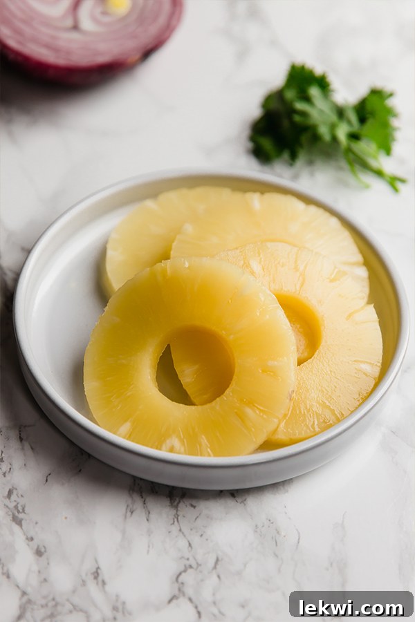 A white dish with four pineapple rings in it.