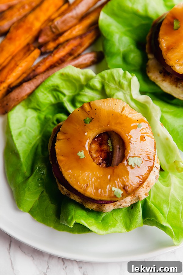 A Hawaiian Teriyaki Chicken burger topped with pineapple and on a piece of lettuce.
