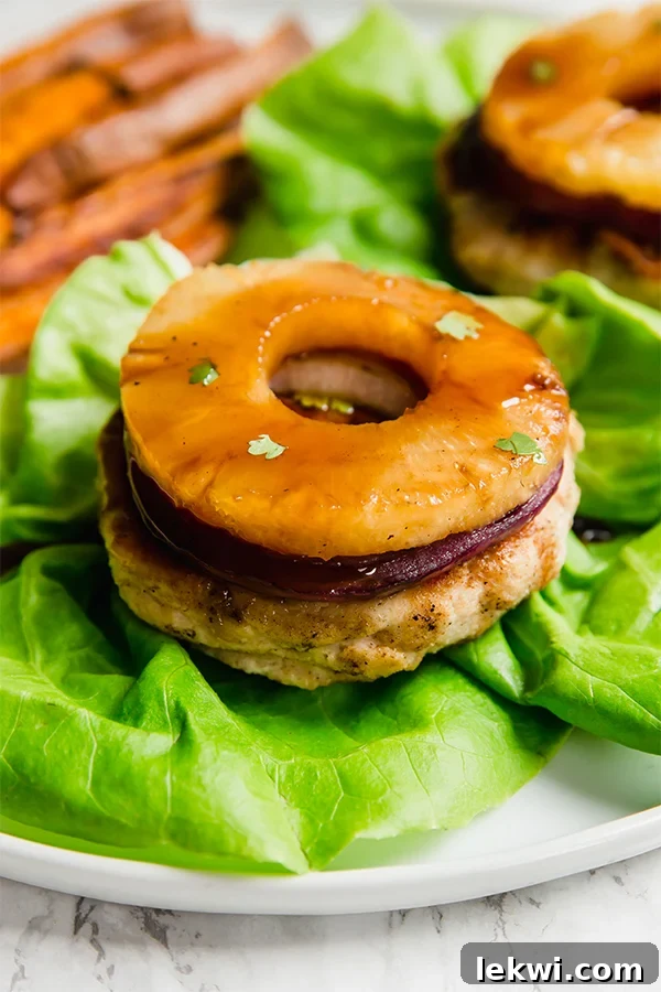 A Hawaiian teriyaki chicken burger topped with pineapple and on a bed of lettuce.