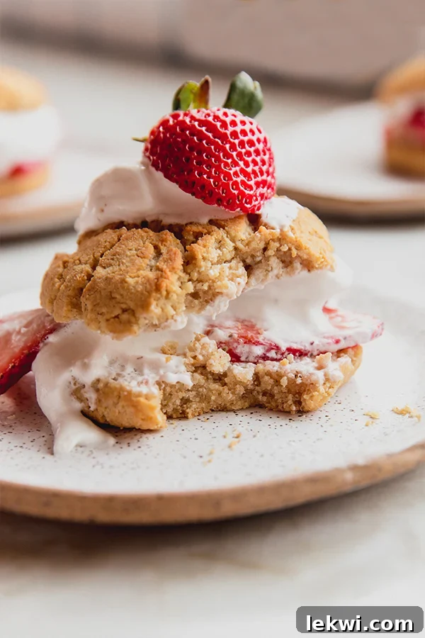 Plate with a strawberry shortcake missing a bite.