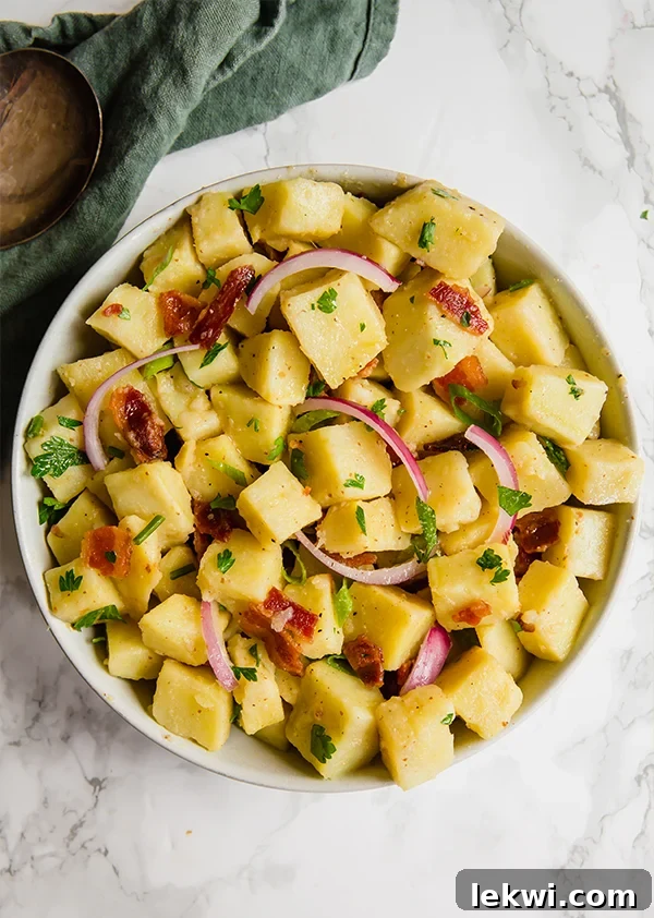 Close-up of a vibrant no-mayo potato salad with fresh herbs and red onion.