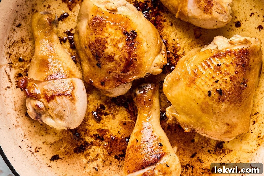 Chicken pieces searing in a hot skillet, developing a golden crust.