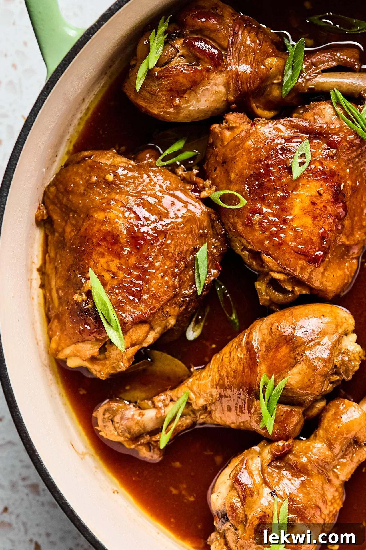 Filipino chicken adobo simmering in a large cast iron pan, ready to be served.