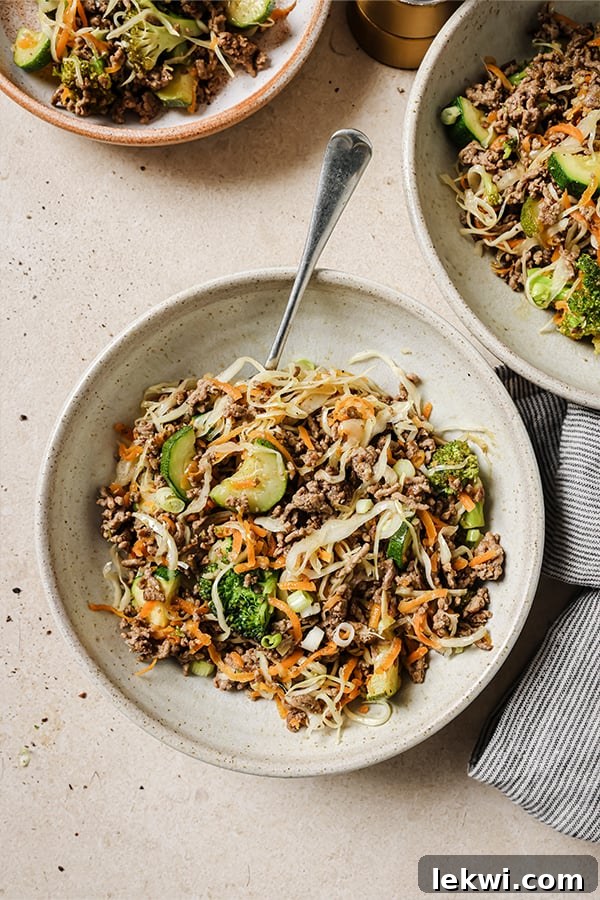 Plate of ground beef stir fry with a fork, garnished with fresh green onions.