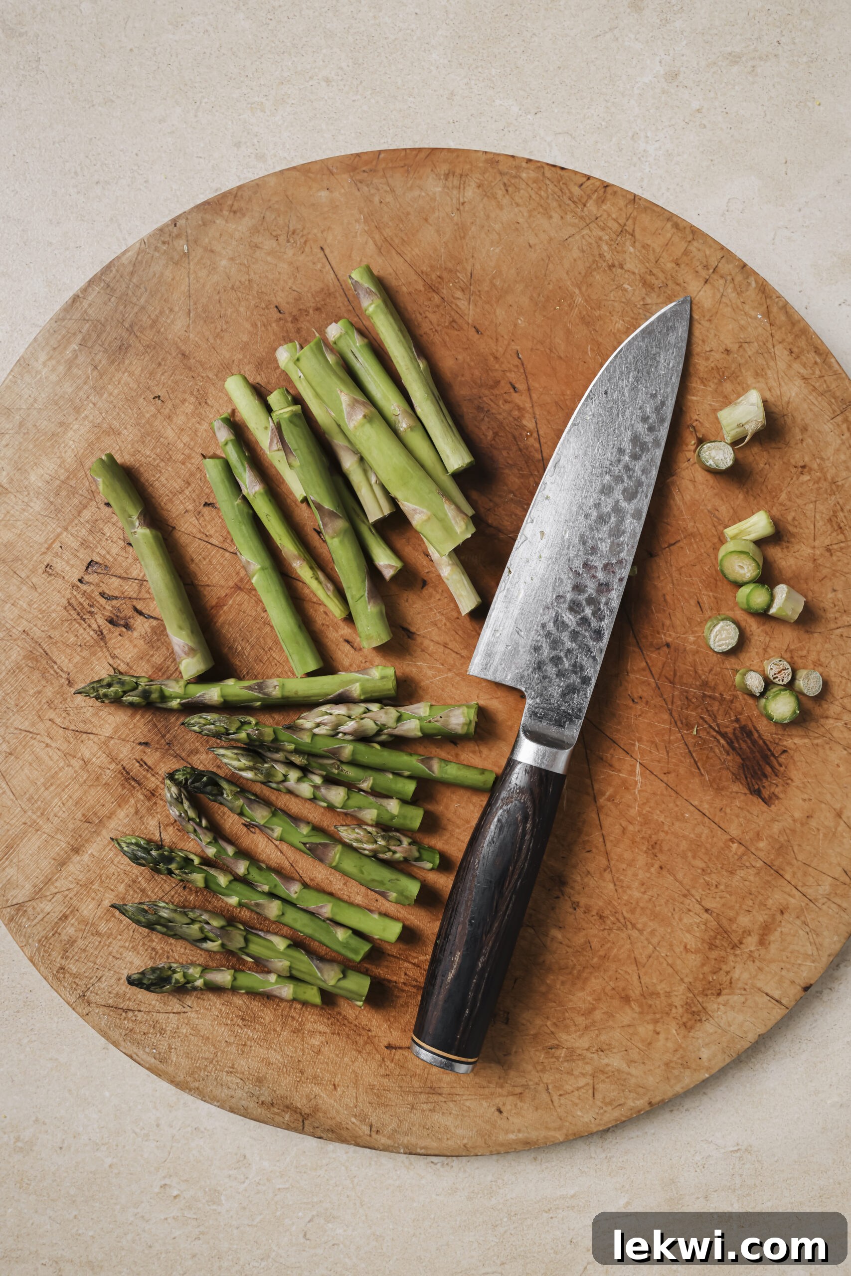 Asparagus being chopped on a wooden cutting board.