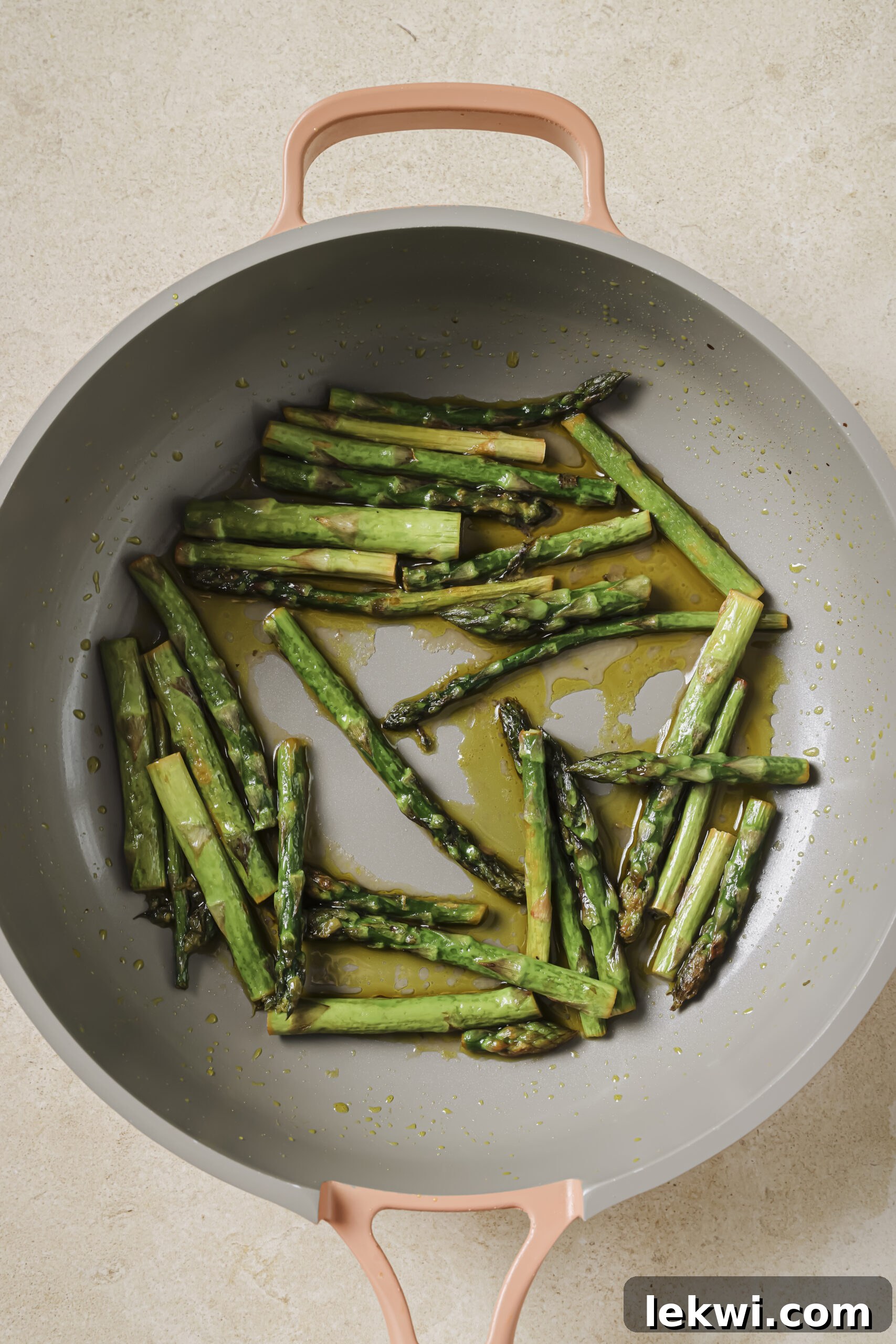 Asparagus being cooked in a pan with oil.