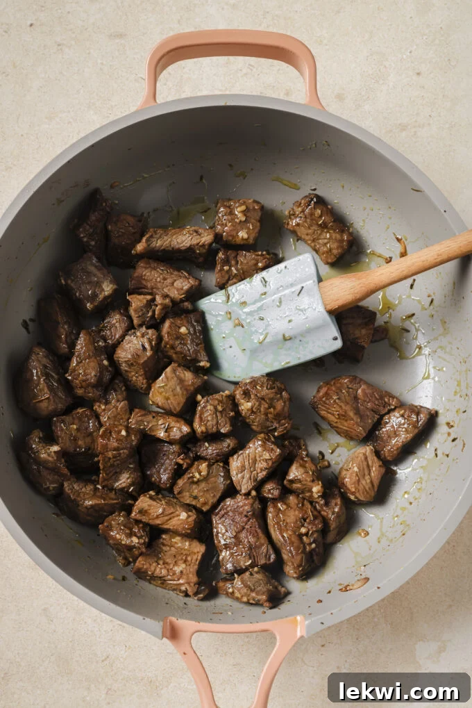 Cubed steak bites being cooked in a pan.