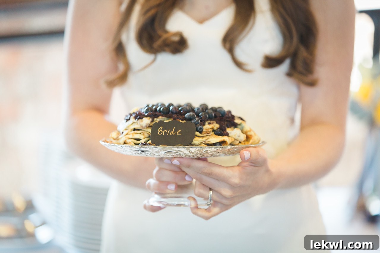 Bride holding her paleo crepe wedding cake with blueberry sauce.
