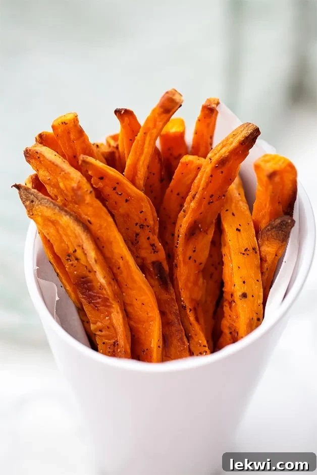 A white cup filled with golden-brown sweet potato fries.