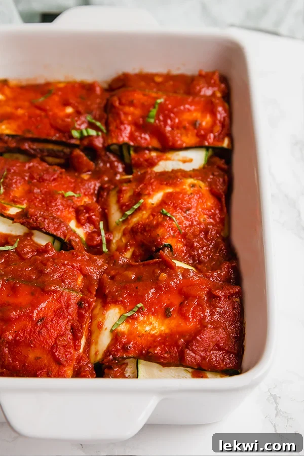 A white ceramic baking dish with layers of zucchini and sauce to make ravioli.