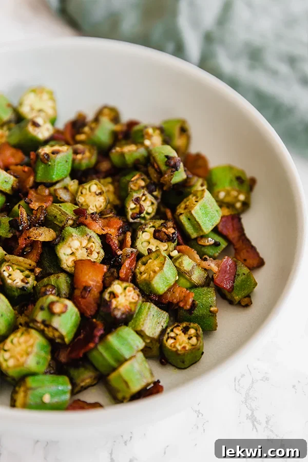 A crisp white bowl overflowing with freshly cooked Southern Bacon and Okra Skillet, showcasing golden-brown okra pieces and savory bacon bits.
