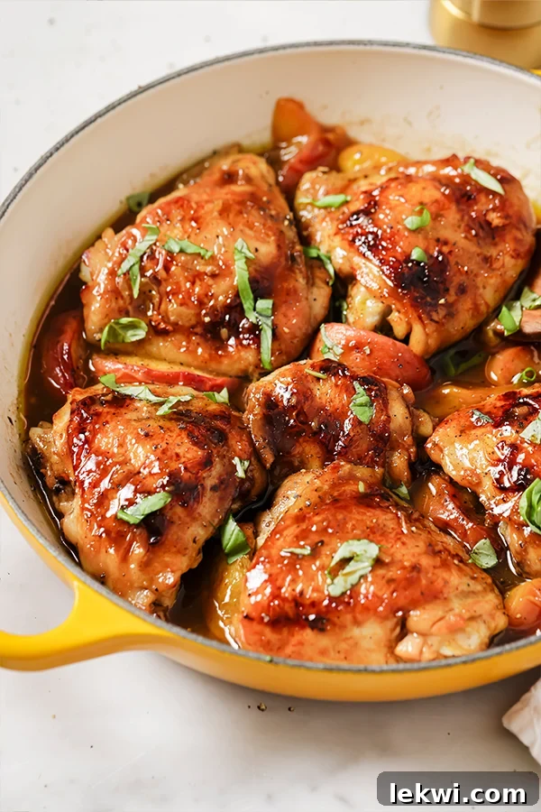 One pan balsamic peach chicken thighs topped with fresh basil in a yellow pan, ready to serve.