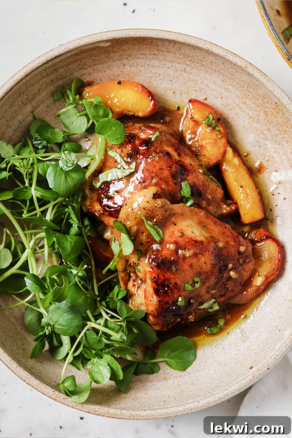 Balsamic chicken thighs and peached served with fresh greens in a large bowl, ready to eat.